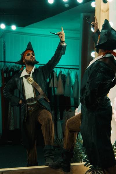 Schauspieler im Piratenkostüm probt vor einem Spiegel in einer Umkleide und übt Gestik und Ausdruck für seine Vorsprechrolle.