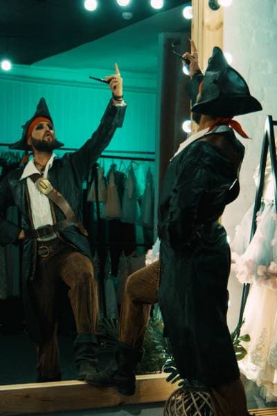 Schauspieler im Piratenkostüm probt vor einem Spiegel in einer Umkleide und übt Gestik und Ausdruck für seine Vorsprechrolle.